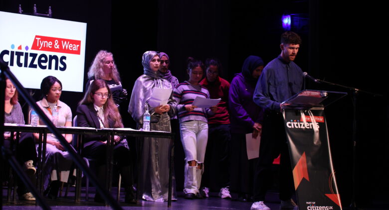 Image shows young people speaking on a stage
